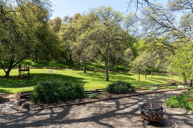 view of property's community with a lawn and an outdoor fire pit