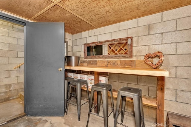 bar featuring concrete block wall and concrete floors