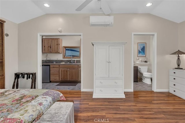bedroom featuring connected bathroom, vaulted ceiling, a sink, and a wall mounted air conditioner