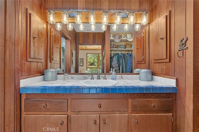 bathroom with vanity, wood walls, and a walk in closet