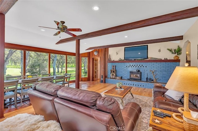 living area with ceiling fan, a wood stove, beam ceiling, wood finished floors, and recessed lighting