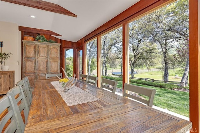 unfurnished sunroom with wooden walls, vaulted ceiling with beams, and wood finished floors