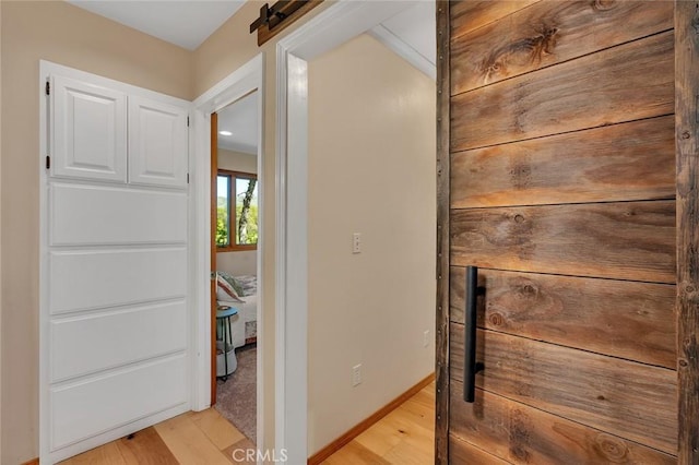 hallway with a barn door and light wood-style flooring