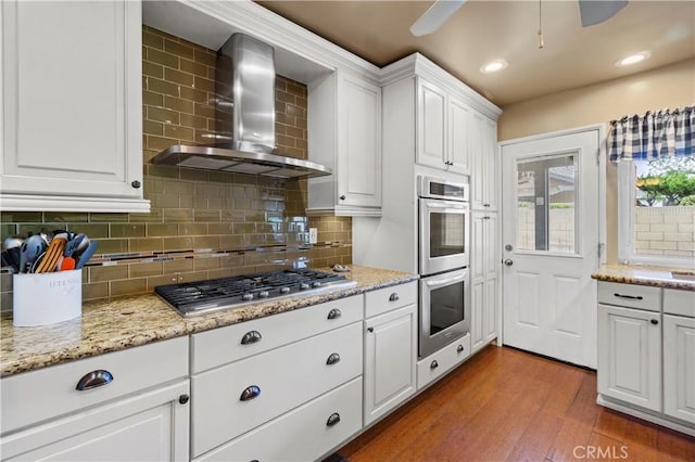 805 W Brentwood Ave, Orange, CA 92865 - kitchen with wall chimney exhaust hood, appliances with stainless steel finishes, wood finished floors, tasteful backsplash, and recessed lighting