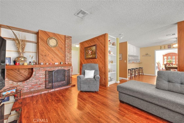 6087 Academy Ave, Riverside, CA 92506 - living room featuring visible vents, wood walls, wood finished floors, and a fireplace