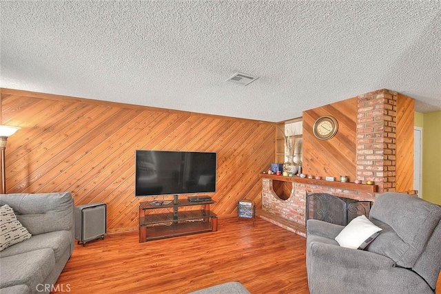 6087 Academy Ave, Riverside, CA 92506 - living area with wooden walls, visible vents, wood finished floors, and a textured ceiling
