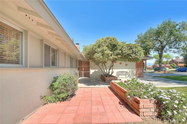 6087 Academy Ave, Riverside, CA 92506 - view of home's exterior featuring a chimney, a vegetable garden, a patio, and stucco siding