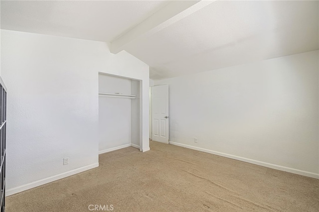 unfurnished bedroom with a closet, carpet flooring, baseboards, and lofted ceiling with beams