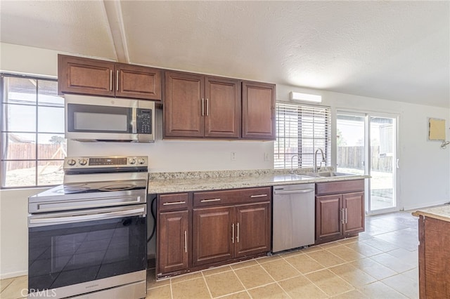 kitchen featuring a textured ceiling, light countertops, a sink, and appliances with stainless steel finishes