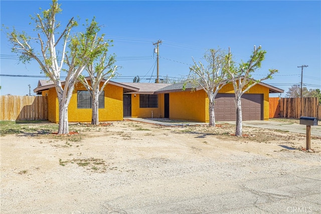 view of front facade with concrete driveway, a garage, stucco siding, and fence