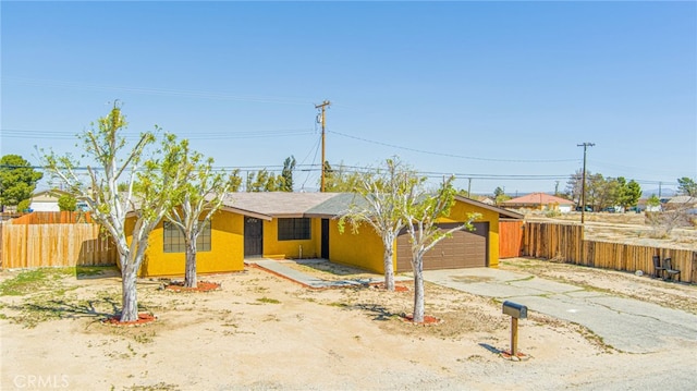 view of front of home with fence, stucco siding, a garage, and concrete driveway
