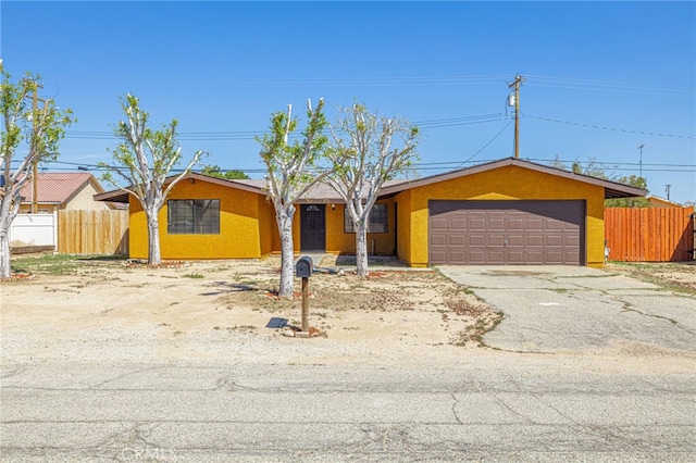 single story home with a garage, aphalt driveway, stucco siding, and fence
