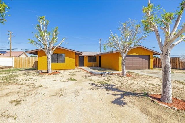 view of front of property with an attached garage, concrete driveway, stucco siding, and fence