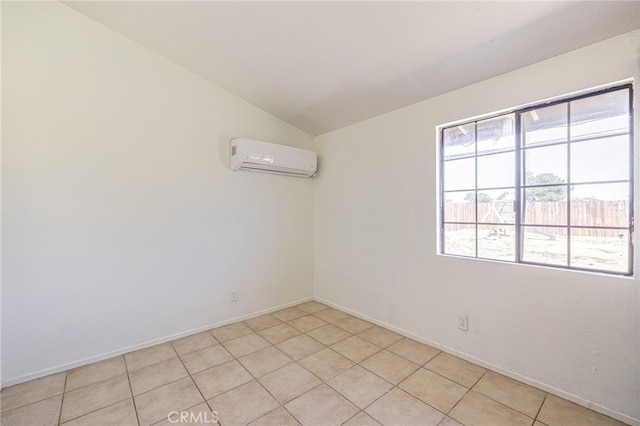 spare room featuring light tile patterned floors, baseboards, lofted ceiling, and a wall unit AC