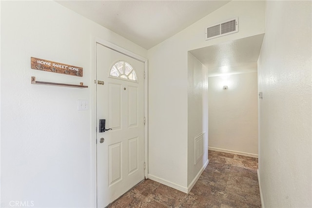 foyer entrance featuring visible vents, baseboards, and stone finish floor