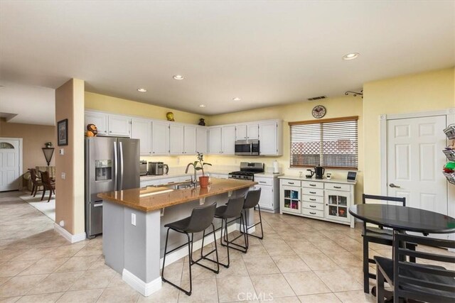 29567 Cool Meadow Dr, Menifee, CA 92584 - kitchen with stainless steel appliances, light tile patterned floors, white cabinets, a breakfast bar area, and recessed lighting