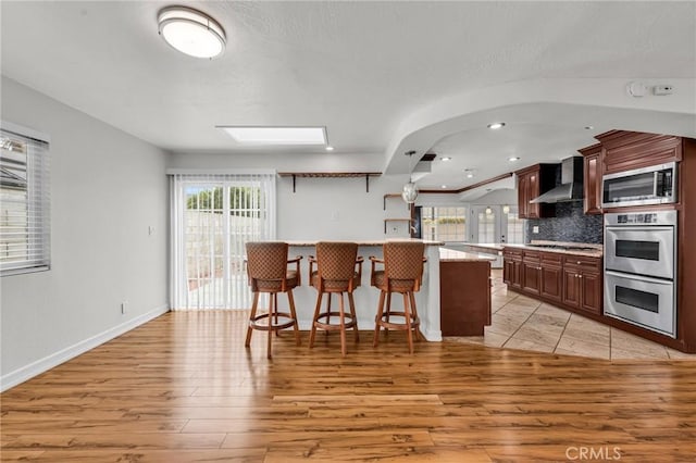 12195 Monte Vista Ave, Chino, CA 91710 - kitchen with a kitchen breakfast bar, light countertops, wall chimney exhaust hood, decorative backsplash, and appliances with stainless steel finishes
