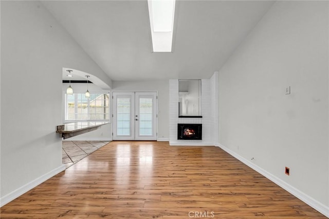 12195 Monte Vista Ave, Chino, CA 91710 - unfurnished living room featuring vaulted ceiling with skylight, french doors, baseboards, and wood finished floors
