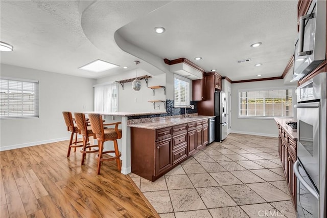 12195 Monte Vista Ave, Chino, CA 91710 - kitchen featuring visible vents, a sink, a breakfast bar, a textured ceiling, and stainless steel appliances