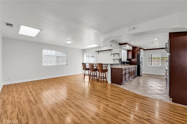 12195 Monte Vista Ave, Chino, CA 91710 - kitchen with light wood-style floors, a kitchen bar, visible vents, open floor plan, and baseboards