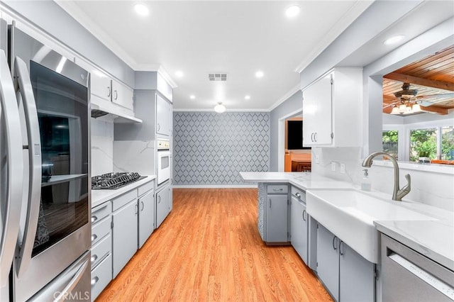 kitchen featuring visible vents, appliances with stainless steel finishes, a sink, wallpapered walls, and gray cabinetry
