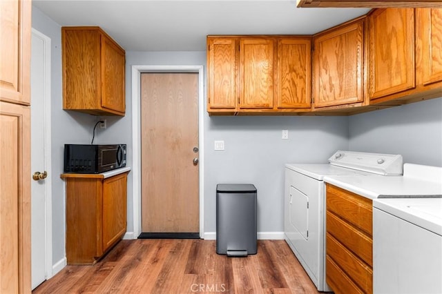 washroom featuring separate washer and dryer, baseboards, cabinet space, and wood finished floors