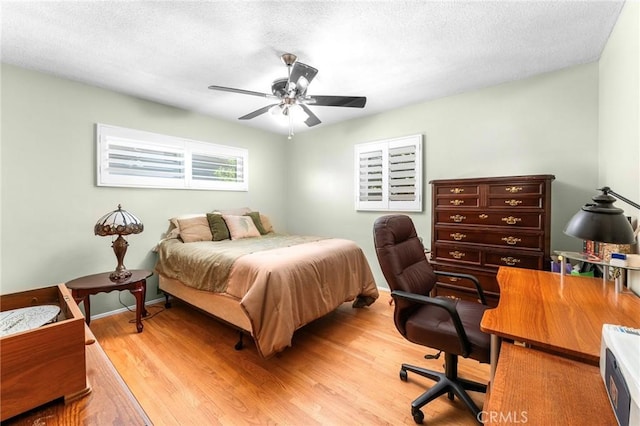 bedroom with baseboards, light wood-type flooring, a textured ceiling, and a ceiling fan