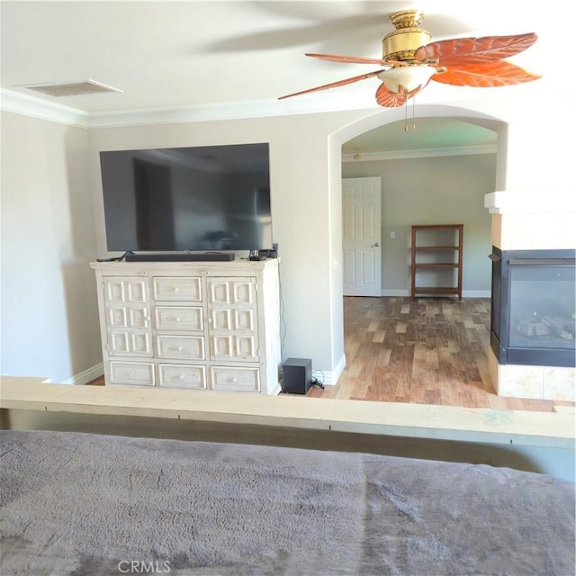 24963 Sunset Vista Ave, Menifee, CA 92584 - living area featuring ornamental molding, ceiling fan, arched walkways, wood finished floors, and a multi sided fireplace