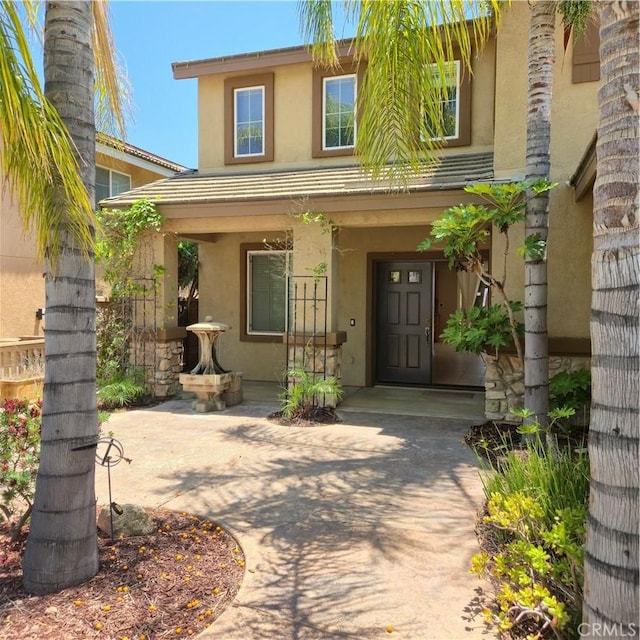 24963 Sunset Vista Ave, Menifee, CA 92584 - doorway to property with stucco siding and a porch