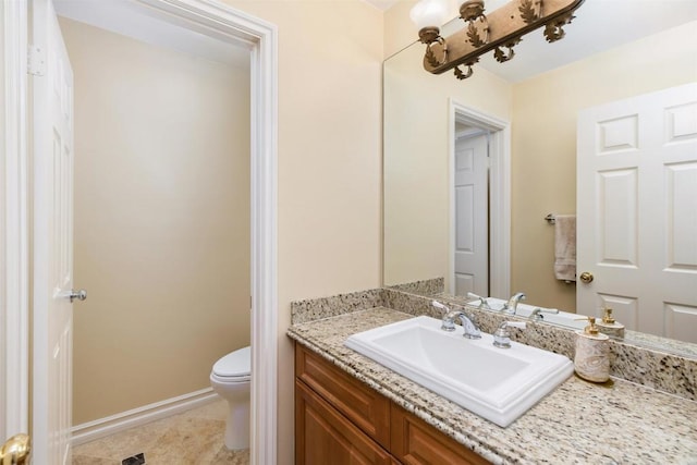 bathroom with vanity, baseboards, and toilet