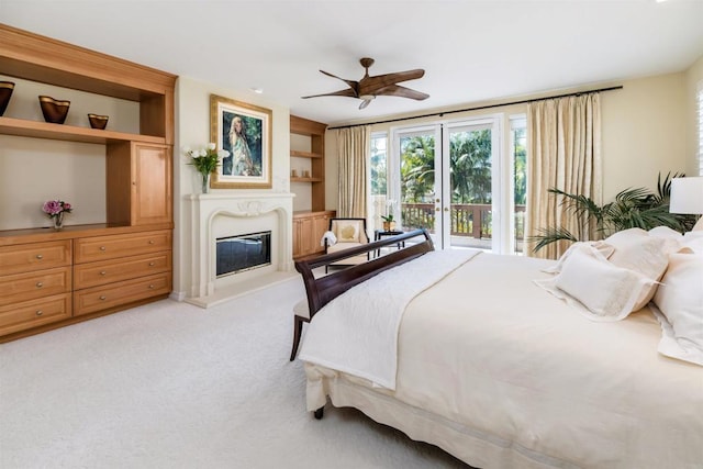 bedroom featuring a glass covered fireplace, carpet, access to exterior, and a ceiling fan