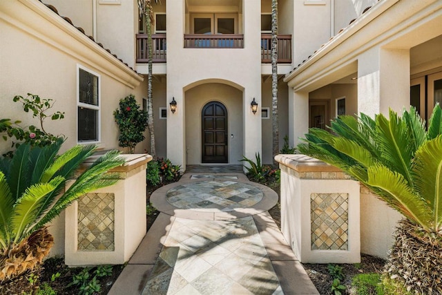 entrance to property featuring a balcony and stucco siding