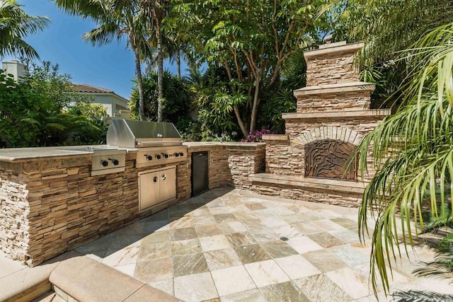 view of patio / terrace with area for grilling, an outdoor stone fireplace, and exterior kitchen