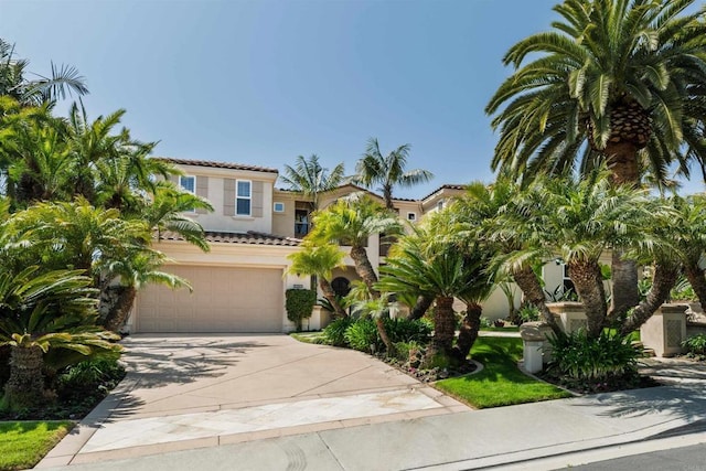 mediterranean / spanish home featuring a tiled roof, concrete driveway, stucco siding, and a garage