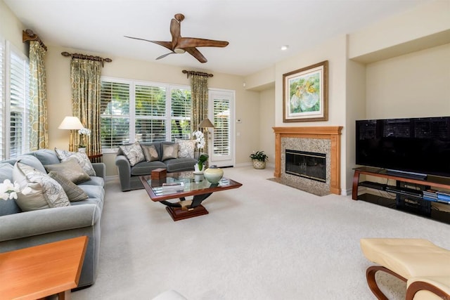 carpeted living room featuring a premium fireplace, baseboards, and a ceiling fan