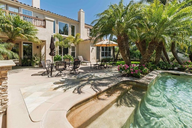 exterior space with a patio area, an outdoor pool, stucco siding, and a chimney