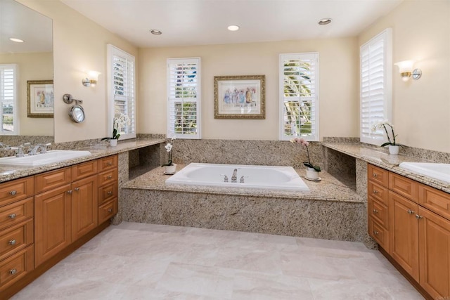 full bathroom with two vanities, a garden tub, and a sink