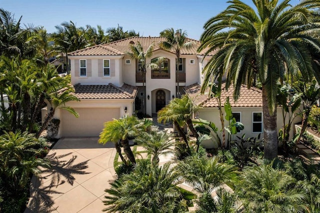 mediterranean / spanish-style home with a tiled roof, driveway, stucco siding, and a garage