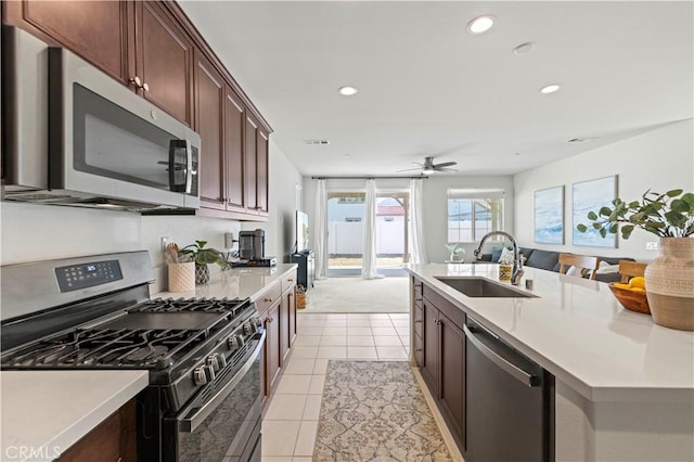 kitchen with a sink, light countertops, light tile patterned flooring, and stainless steel appliances