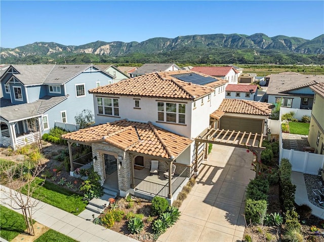 mediterranean / spanish-style home with a mountain view, a tile roof, fence, and covered porch