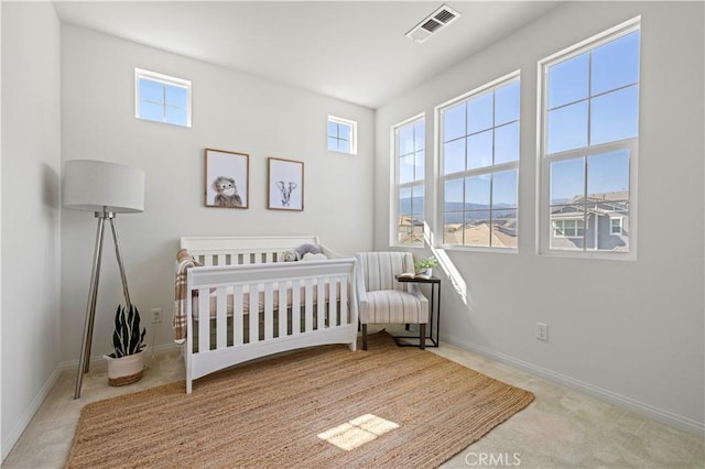 carpeted bedroom featuring visible vents, multiple windows, baseboards, and a nursery area