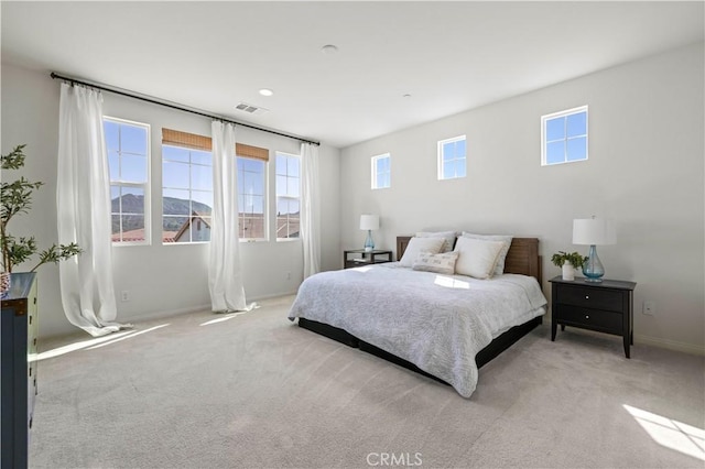 bedroom with visible vents, multiple windows, and light colored carpet