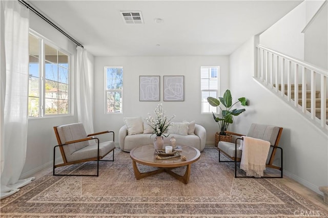 living room with baseboards, visible vents, and stairs