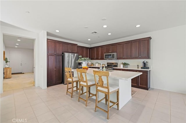 kitchen with a kitchen bar, appliances with stainless steel finishes, light countertops, and recessed lighting