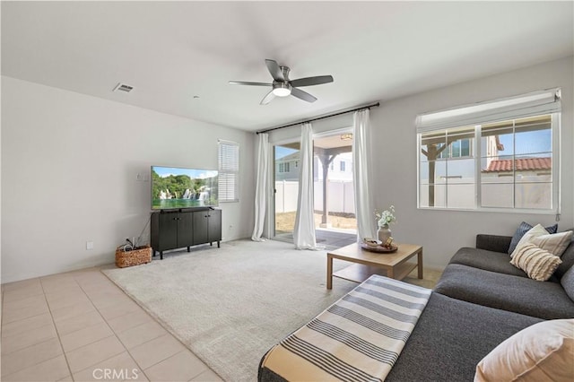 carpeted living area featuring tile patterned flooring, visible vents, and a ceiling fan