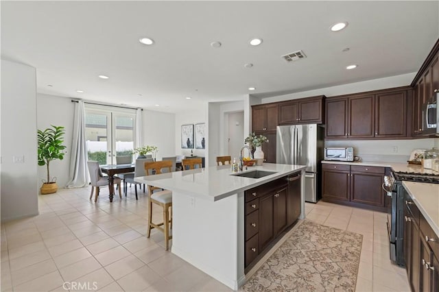 kitchen with an island with sink, light countertops, visible vents, stainless steel appliances, and a sink