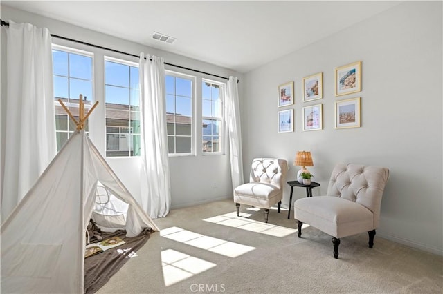 living area with baseboards, visible vents, and carpet floors