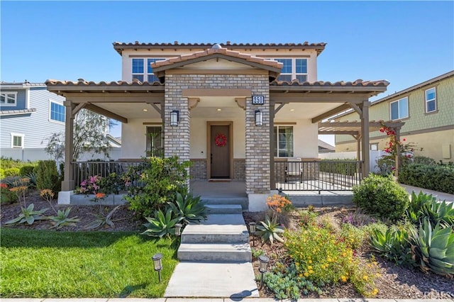 mediterranean / spanish-style home featuring brick siding, a porch, and stucco siding