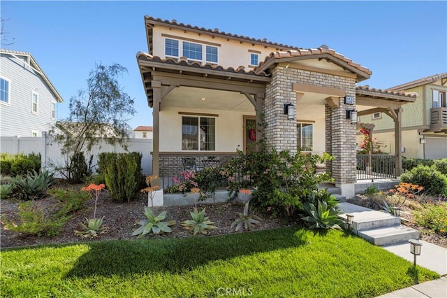 mediterranean / spanish home with a porch, a tiled roof, stucco siding, and fence