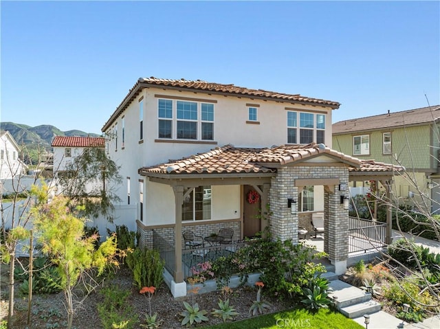 mediterranean / spanish home with a tiled roof, covered porch, and stucco siding